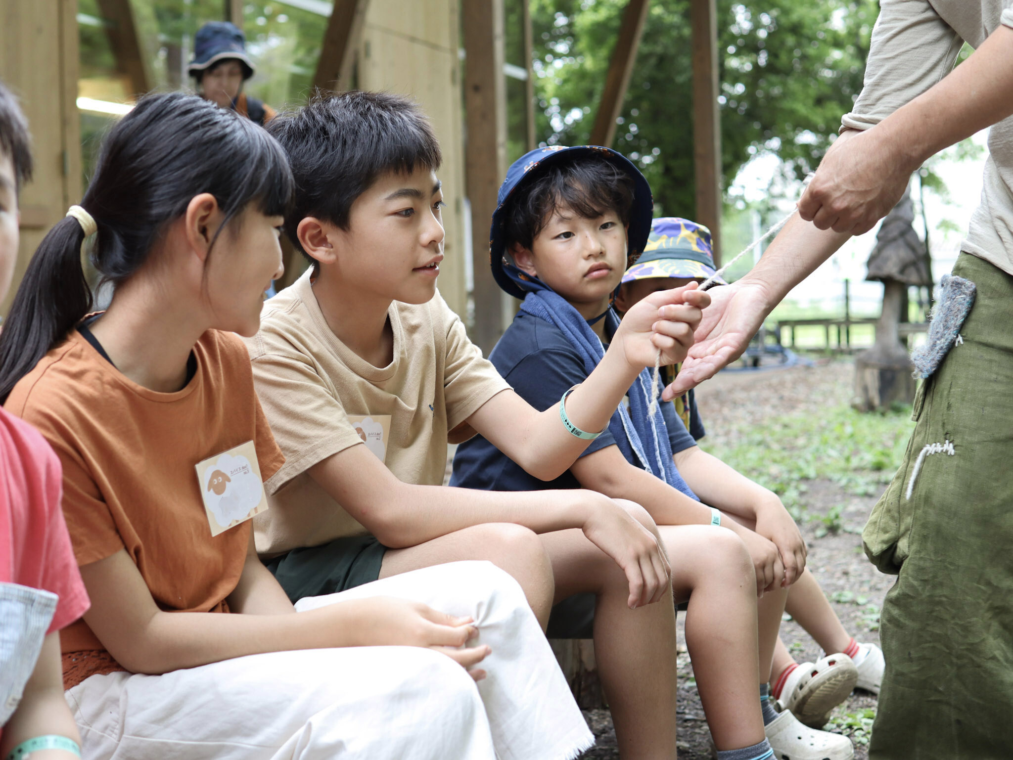 丸岡さんがその場で撚った毛糸をさわる子どもたち。