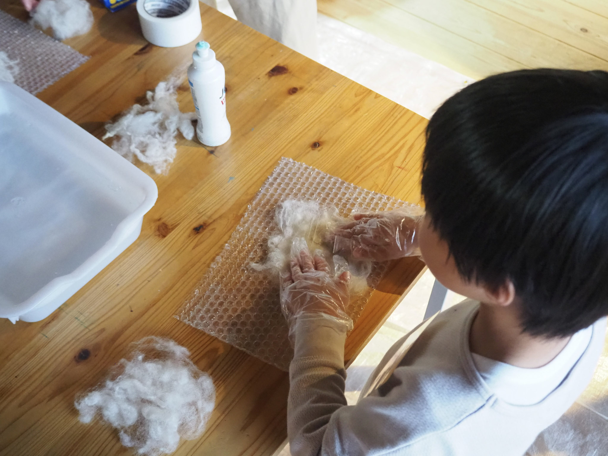 重ねた羊毛に中性洗剤を混ぜたお湯をかけ、繊維をゆらして固めていく。