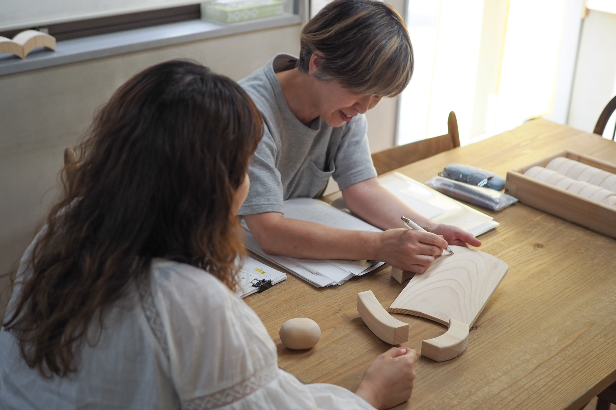 響hibi-ki STOREの店長と商品開発の相談をする山本さん(写真右)。