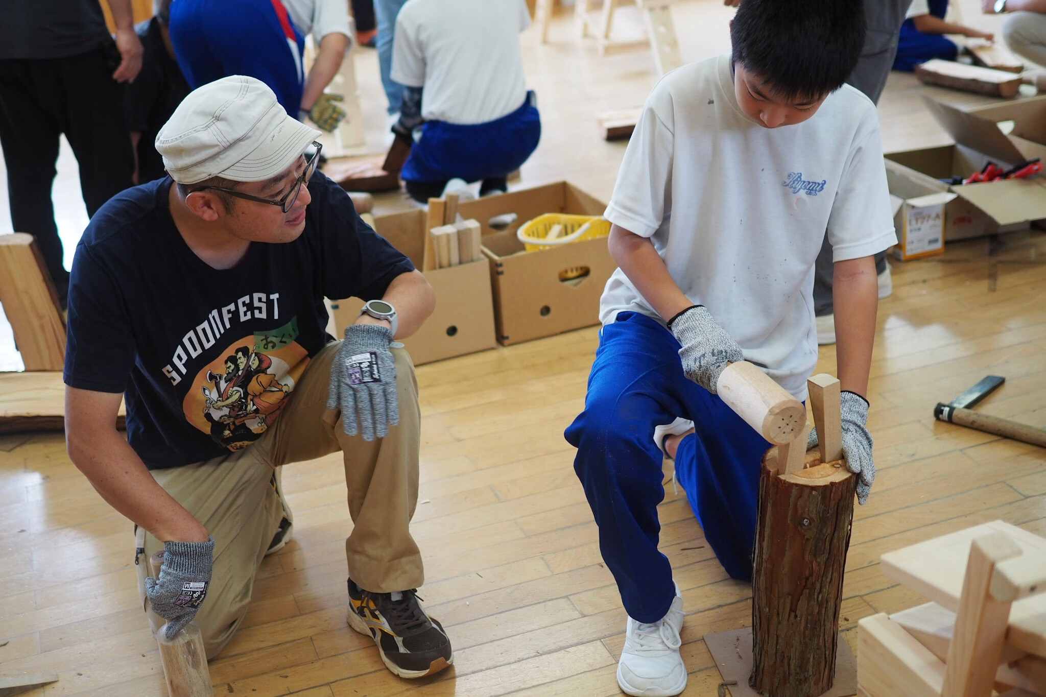 割れ目にクサビを打ち込む児童を見守る奥井さん。